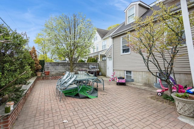 view of patio with fence, outdoor dining space, and a grill