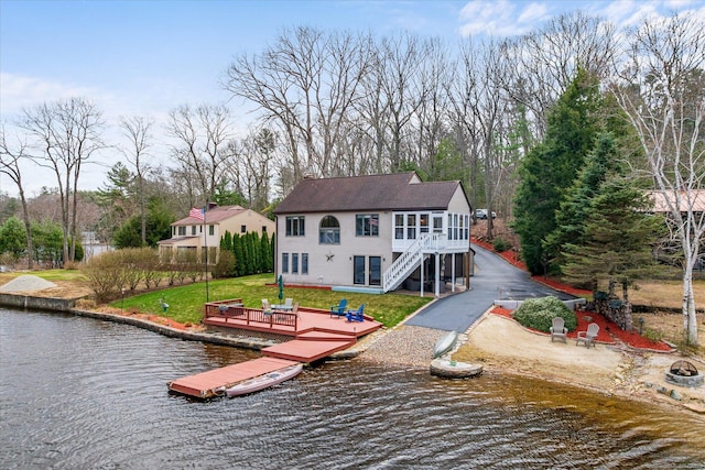 rear view of house featuring a deck with water view and a lawn