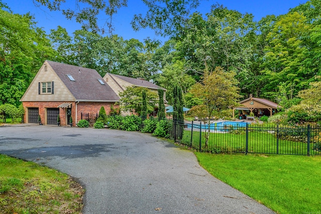 view of side of home featuring brick siding, a yard, driveway, and fence