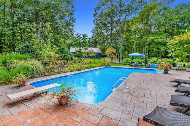 pool with a patio, a diving board, and fence