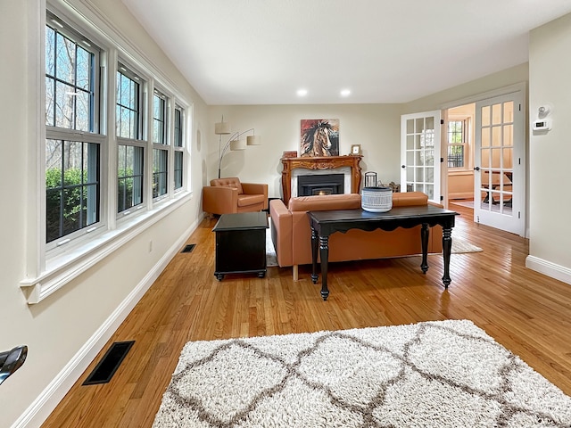 living room featuring visible vents, a fireplace, baseboards, recessed lighting, and light wood-style flooring