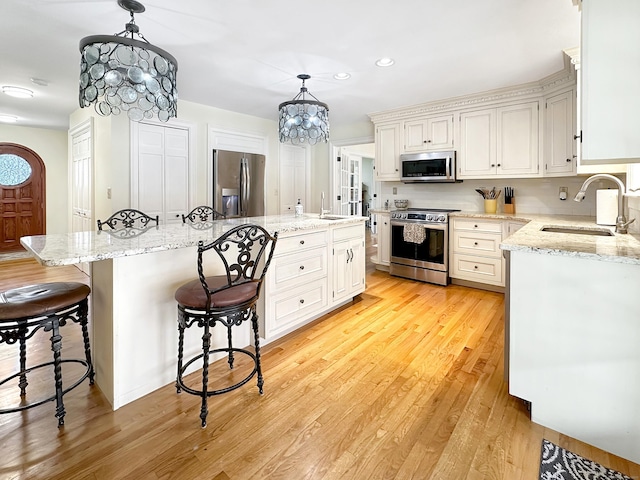 kitchen with a kitchen island, appliances with stainless steel finishes, a sink, and light wood-style floors
