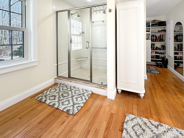 bathroom with baseboards, a shower stall, and wood finished floors