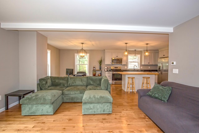 3 Henry Rd, Enfield, CT 06082 - living room featuring an inviting chandelier, beamed ceiling, and light wood-type flooring