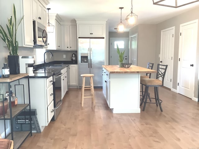 3 Henry Rd, Enfield, CT 06082 - kitchen with appliances with stainless steel finishes, butcher block countertops, a kitchen island, a kitchen bar, and pendant lighting