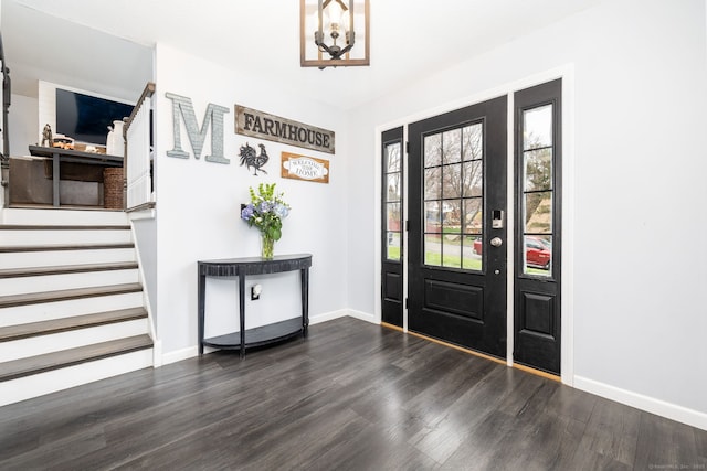 entryway featuring stairway, an inviting chandelier, wood finished floors, and baseboards
