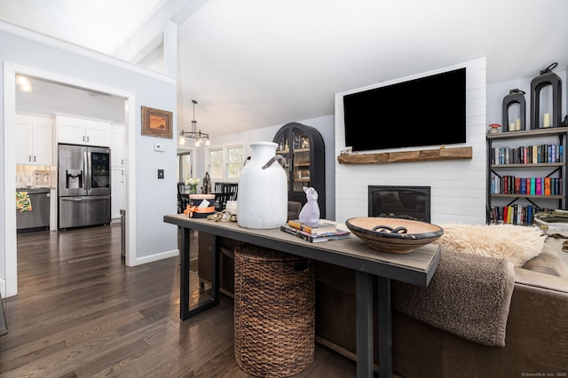 living area with dark wood finished floors, a chandelier, a large fireplace, and vaulted ceiling with beams