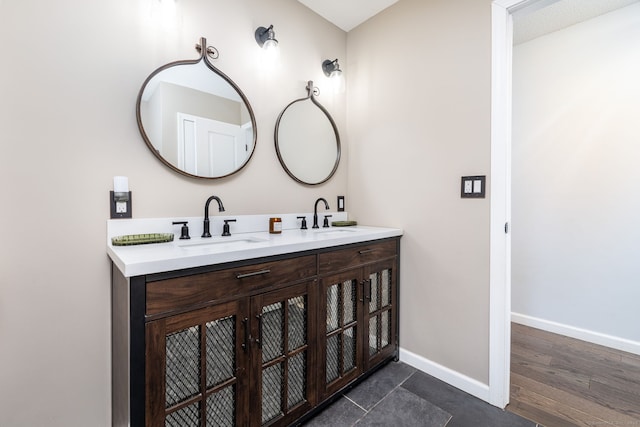 bathroom with double vanity, baseboards, and a sink