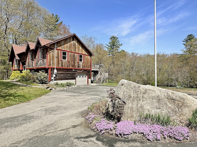 view of side of property with a garage, aphalt driveway, and stairway