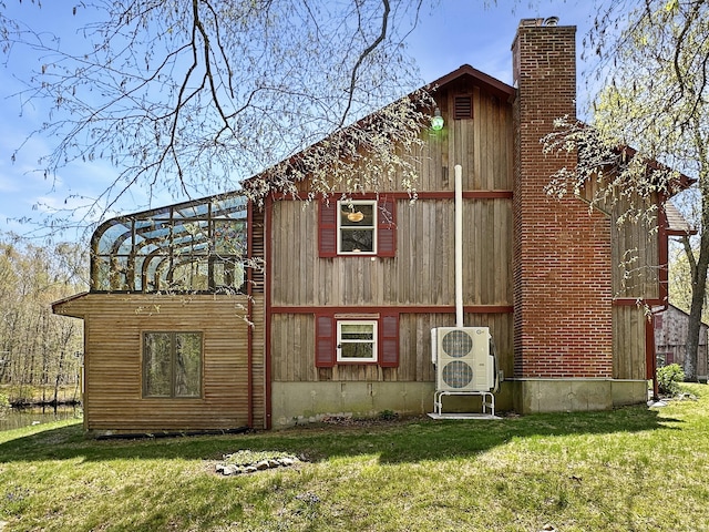 exterior space with a lawn, ac unit, and a chimney
