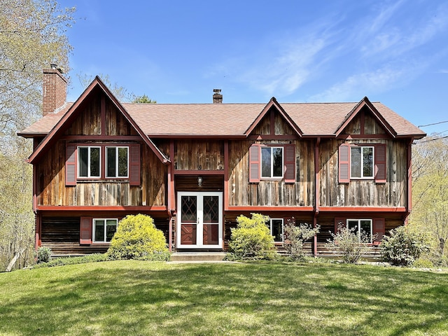 view of front of property featuring a chimney, roof with shingles, and a front yard