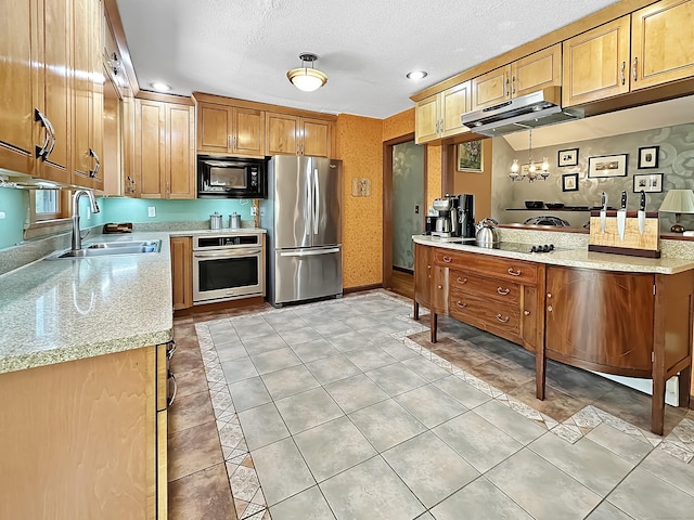 kitchen featuring brown cabinetry, a textured ceiling, a sink, black appliances, and under cabinet range hood