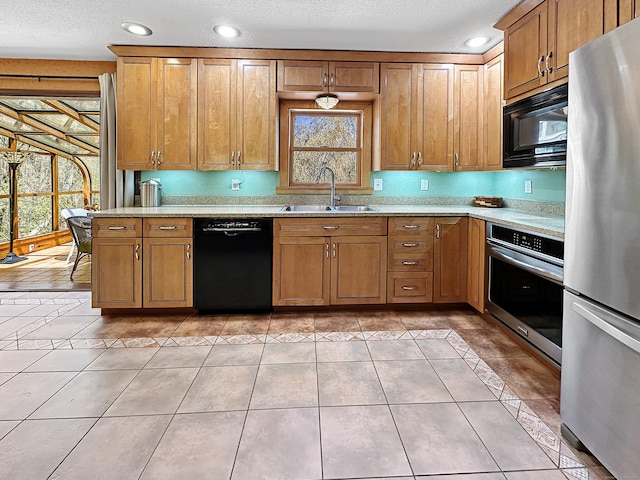 kitchen featuring a sink, brown cabinetry, recessed lighting, light tile patterned floors, and black appliances