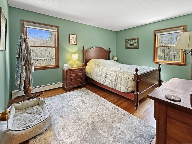 bedroom featuring a textured ceiling, wood finished floors, and baseboard heating