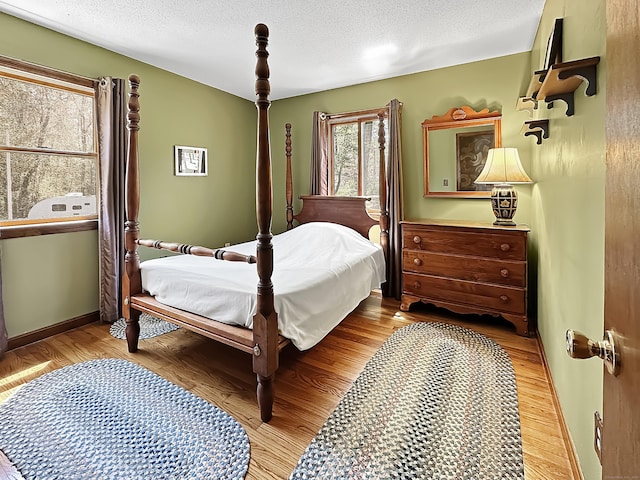 bedroom featuring baseboards, a textured ceiling, and wood finished floors