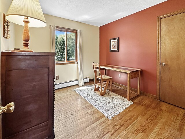 office area featuring baseboards, baseboard heating, and wood finished floors