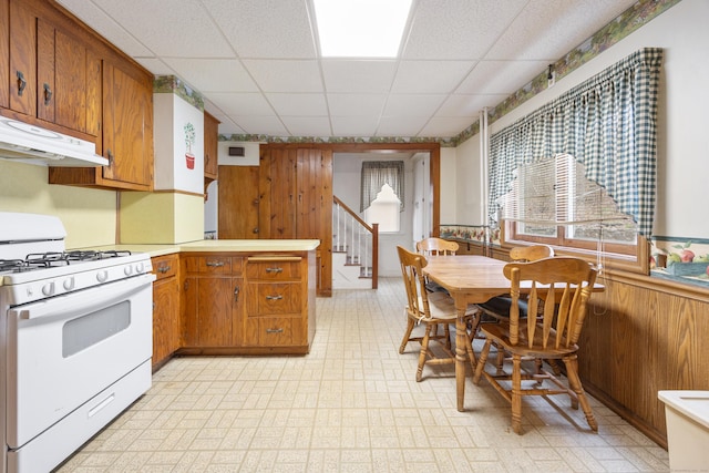 170 Park Rd, Waterbury, CT 06708 - kitchen featuring light floors, white gas range oven, brown cabinets, and a paneled ceiling