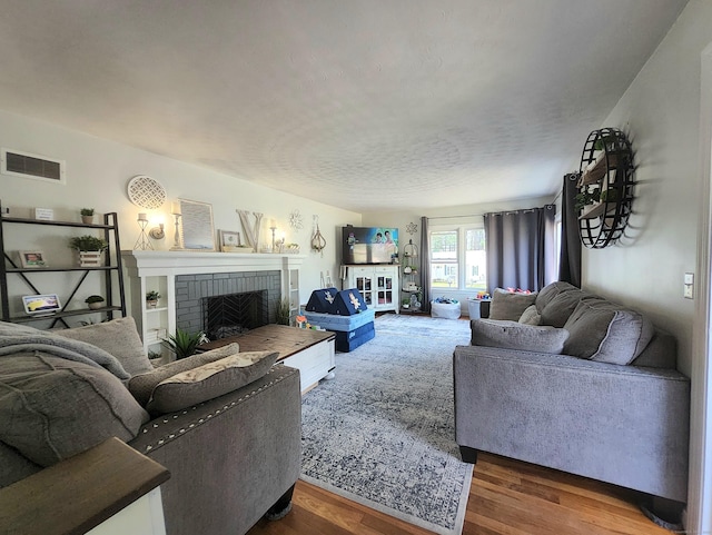 living area featuring visible vents, wood finished floors, and a fireplace