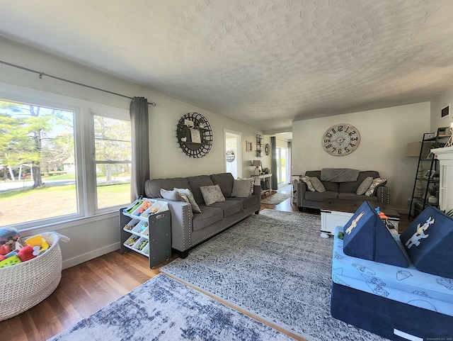 living room with plenty of natural light, a textured ceiling, baseboards, and wood finished floors