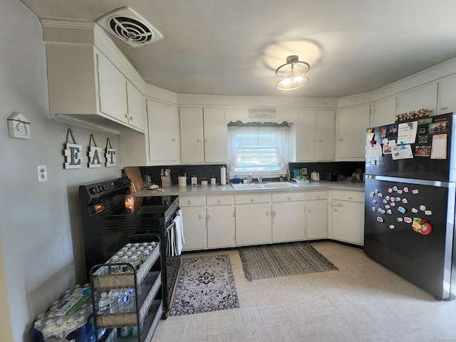 kitchen with white cabinets, light countertops, freestanding refrigerator, visible vents, and black range with electric stovetop