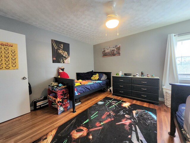 bedroom featuring a ceiling fan, a textured ceiling, and wood finished floors
