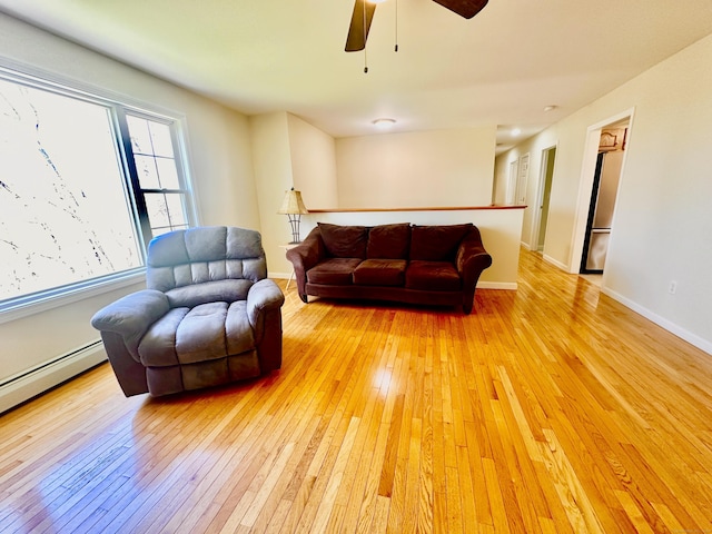 living area featuring baseboards, a ceiling fan, and light wood-style flooring