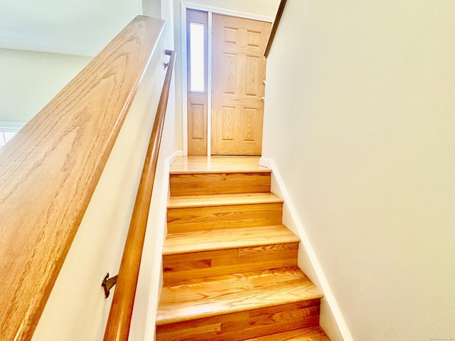 staircase with baseboards and wood finished floors