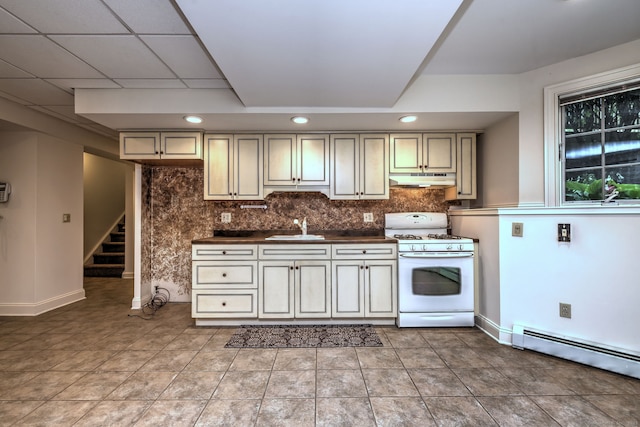 395 Isinglass Rd, Shelton, CT 06484 - kitchen with white gas range, a sink, dark countertops, cream cabinetry, and backsplash