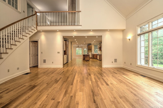 395 Isinglass Rd, Shelton, CT 06484 - unfurnished living room featuring high vaulted ceiling, healthy amount of natural light, stairway, wood finished floors, and crown molding