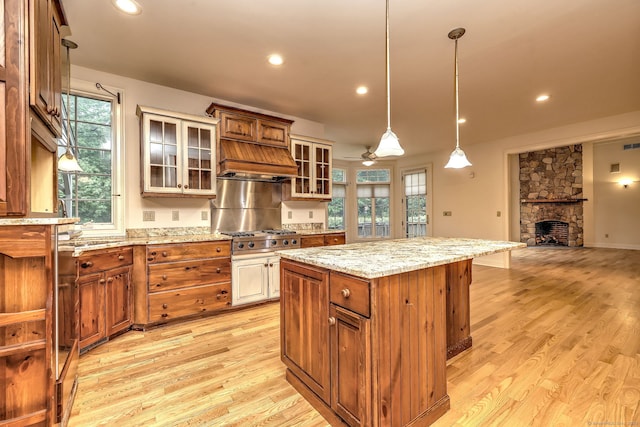 395 Isinglass Rd, Shelton, CT 06484 - kitchen with ceiling fan, light wood-type flooring, a stone fireplace, a center island, and decorative light fixtures