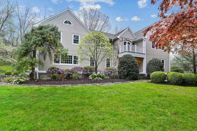 view of front of home featuring a balcony and a front yard
