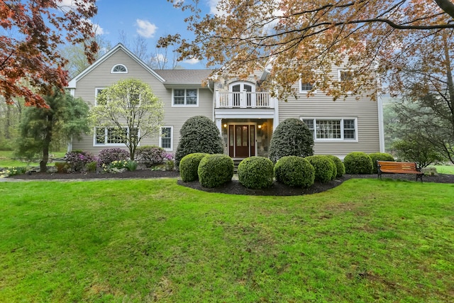 view of front of home with a front yard and a balcony