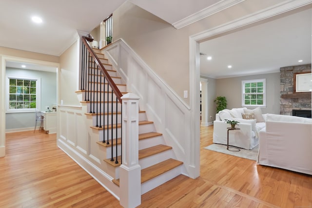 9 Blue Spruce Cir, Weston, CT 06883 - staircase with crown molding, wood finished floors, a fireplace, a decorative wall, and a wainscoted wall