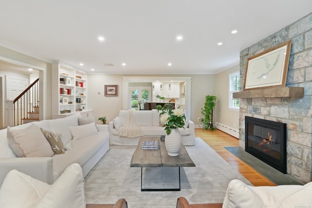 living area with baseboard heating, recessed lighting, a stone fireplace, and light wood finished floors