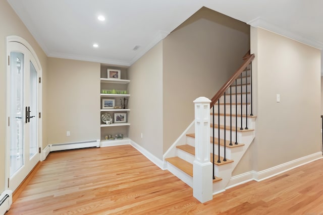 interior space with a baseboard heating unit, wood finished floors, and baseboards