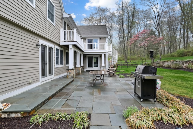 view of patio with stairs, outdoor dining space, a grill, and a balcony