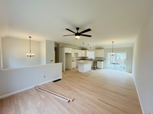 unfurnished living room with baseboards, light wood-style floors, visible vents, and ceiling fan with notable chandelier