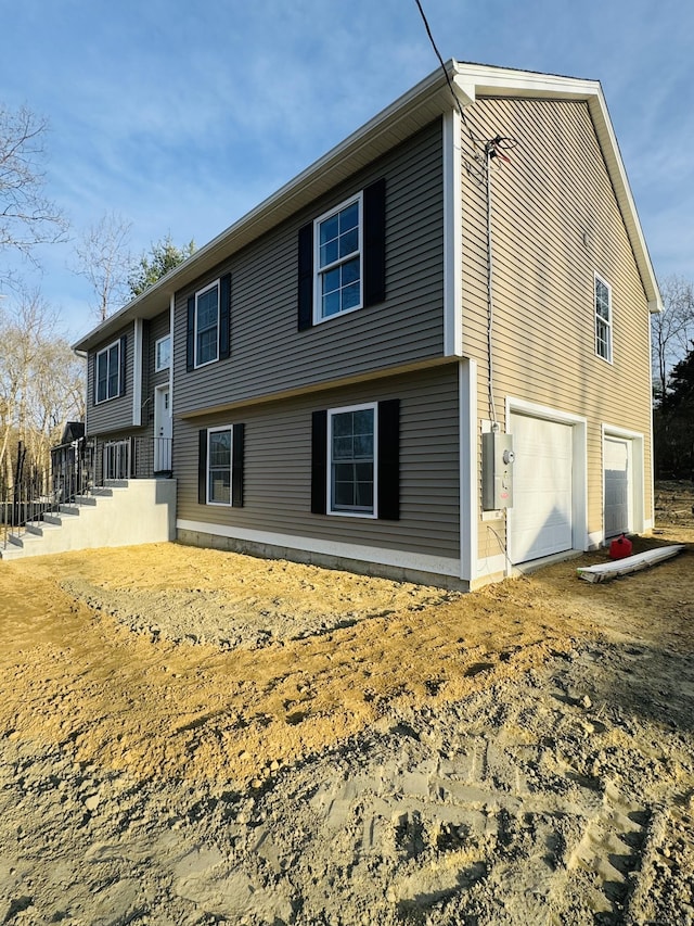 rear view of property featuring an attached garage and driveway