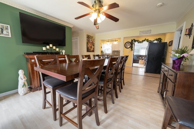 dining space with crown molding, a ceiling fan, and light wood-style flooring