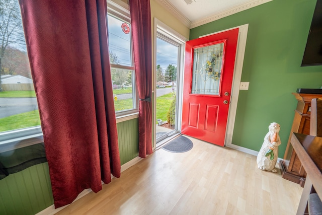 foyer featuring wood finished floors, a healthy amount of sunlight, ornamental molding, and baseboards