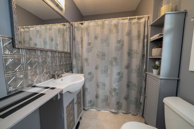 bathroom with a textured ceiling, decorative backsplash, toilet, vanity, and tile patterned flooring