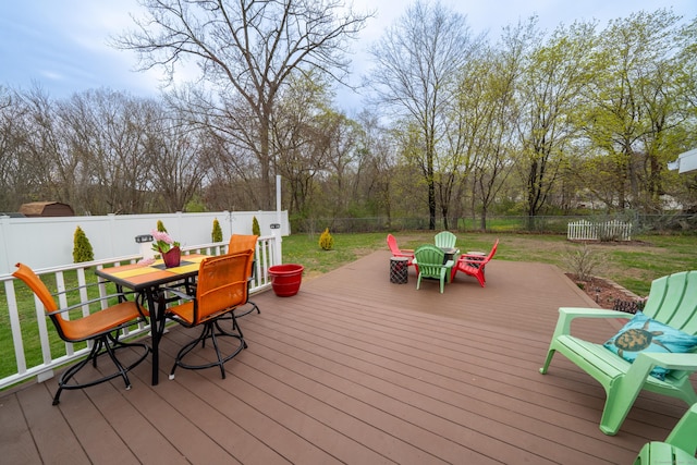 wooden deck with outdoor dining space, a fenced backyard, and a lawn