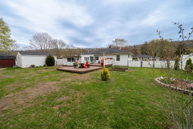 rear view of property with a wooden deck, an outbuilding, a lawn, a shed, and fence