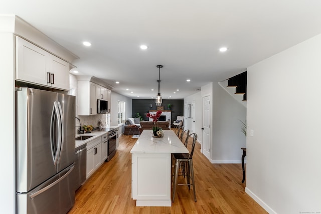 19 Stony Brook Rd, Brookfield, CT 06804 - kitchen with white cabinetry, appliances with stainless steel finishes, a kitchen island, open floor plan, and light wood finished floors