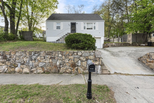 view of front of home with fence, concrete driveway, a front lawn, and a garage