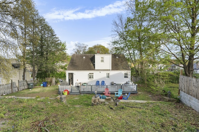 back of property with a yard, fence, a wooden deck, and a chimney