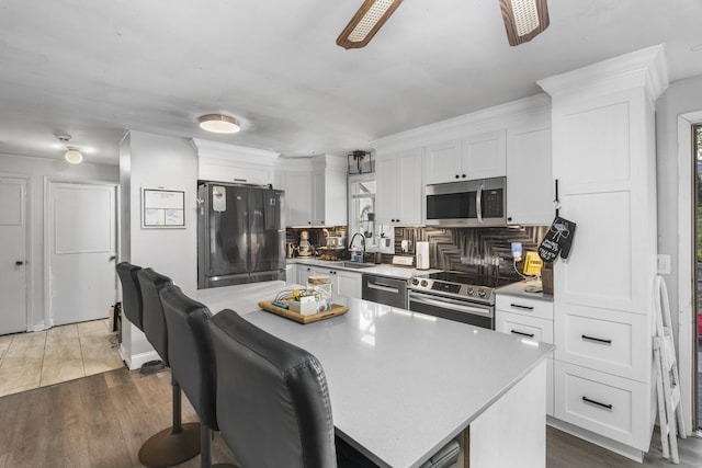 kitchen with a sink, white cabinetry, tasteful backsplash, and stainless steel appliances