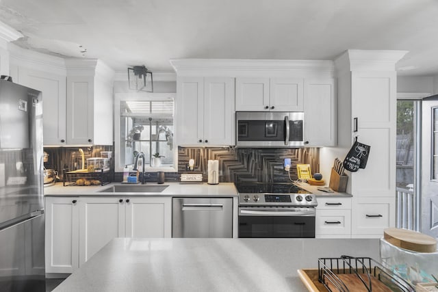 kitchen featuring light countertops, white cabinets, tasteful backsplash, a sink, and appliances with stainless steel finishes