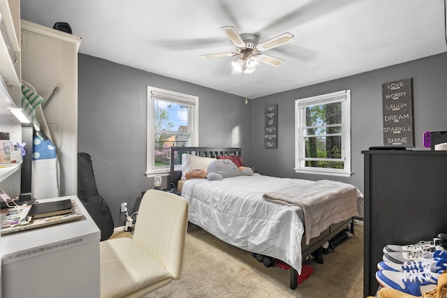 carpeted bedroom featuring multiple windows and a ceiling fan