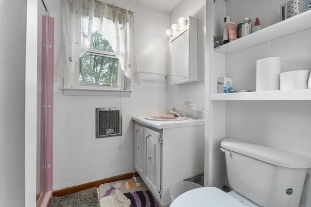 bathroom featuring heating unit, vanity, and toilet